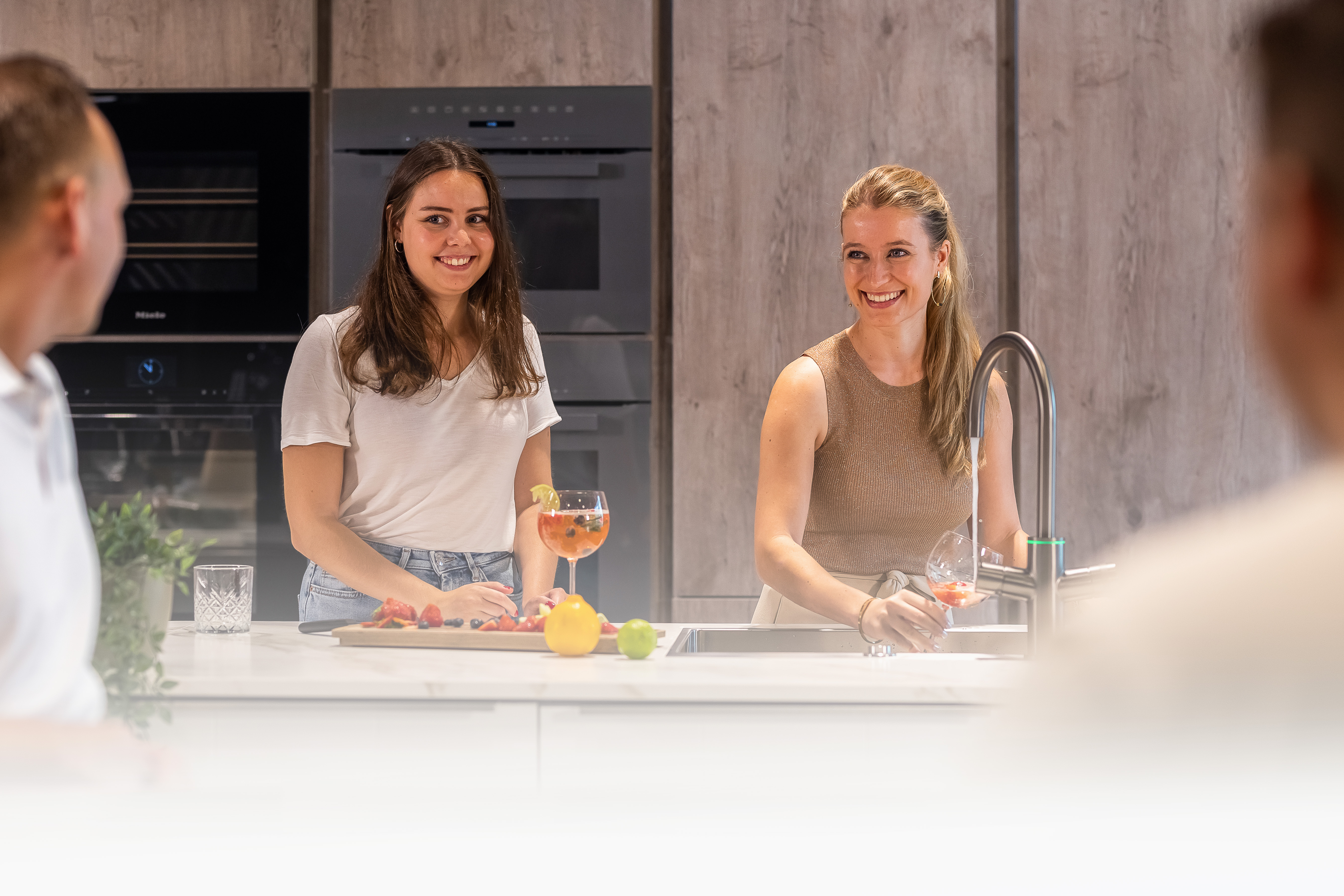 Stemmings billede hvor man kan se to damer ssamt 2 mænd. Pigerne er i gang med at lave cooktail ved brug af vandhanen